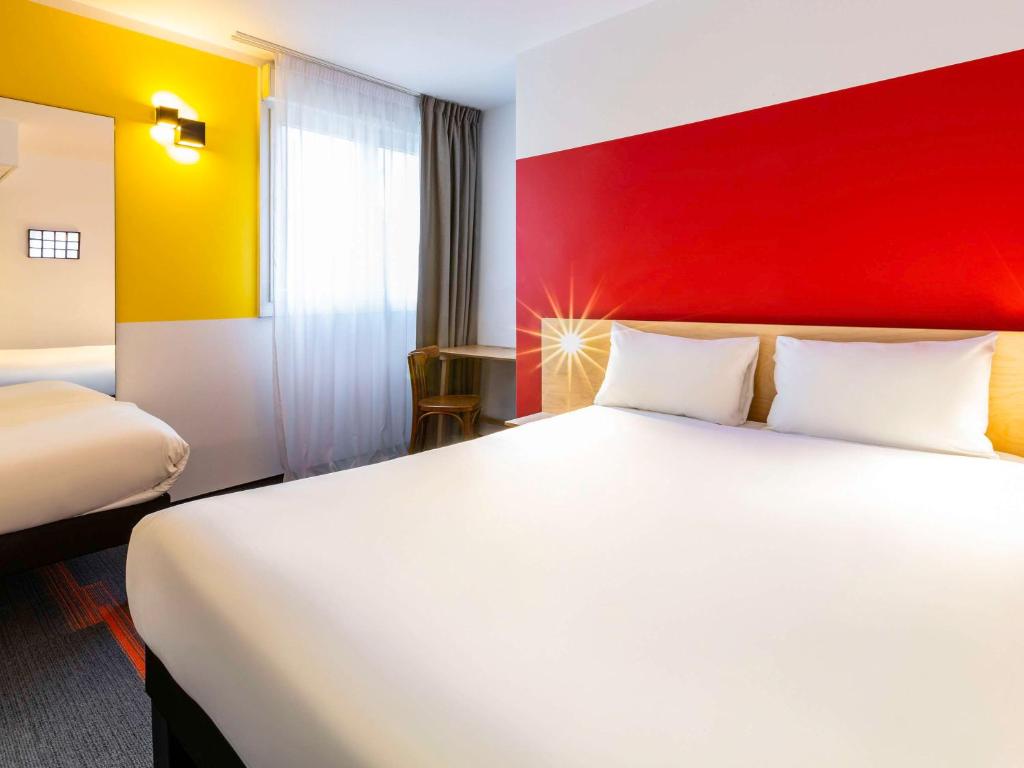 Houdemontにあるgreet Hotel Nancy Sudの白いベッドと赤い壁が備わるホテルルームです。