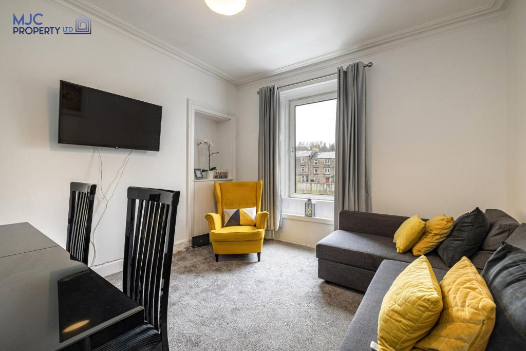 a living room with a gray couch and a yellow chair at Riverside in Hawick