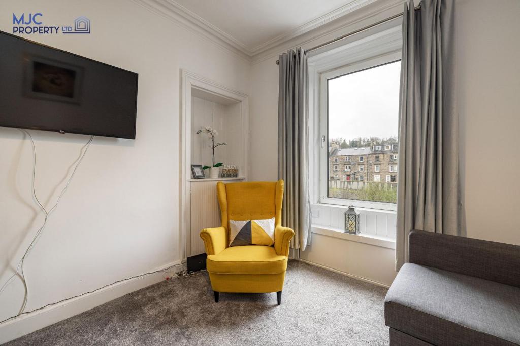 a living room with a yellow chair and a window at Riverside in Hawick