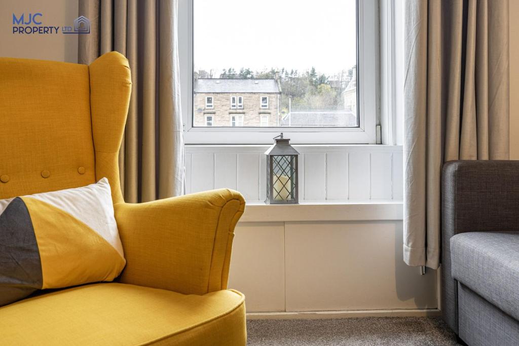 a yellow chair sitting in front of a window at Riverside in Hawick