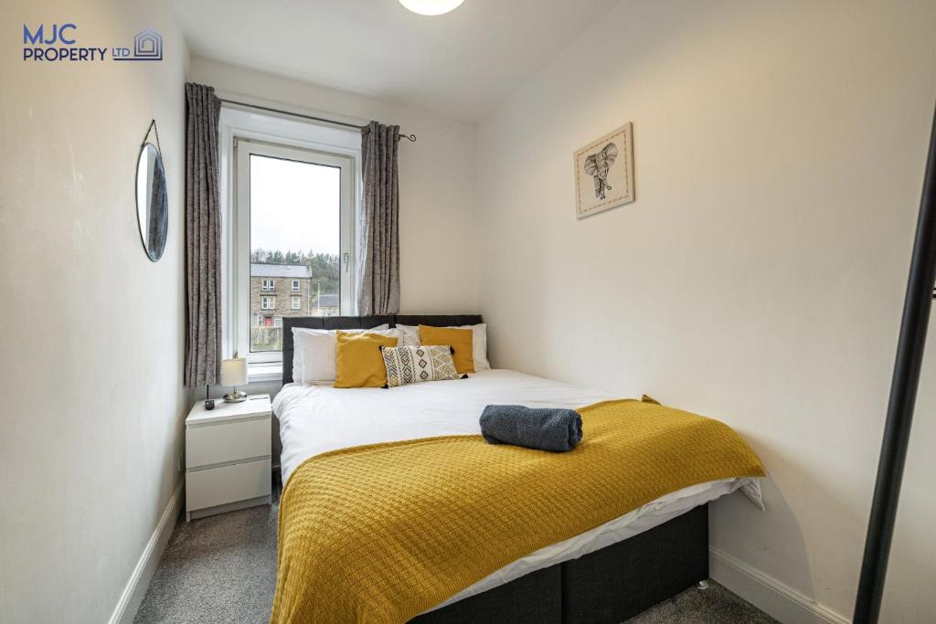 ein Schlafzimmer mit einem Bett mit einer gelben Decke darauf in der Unterkunft Riverside in Hawick