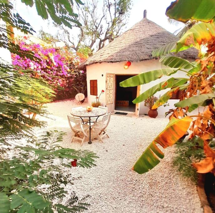 萨利尼亚拉尔Cosy Case avec son Jaccuzi privé Saly的房子前面的一张桌子和几把椅子