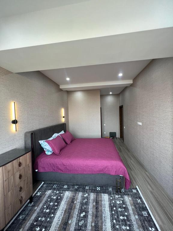 een slaapkamer met een groot bed met paarse lakens bij Platinum in Bisjkek
