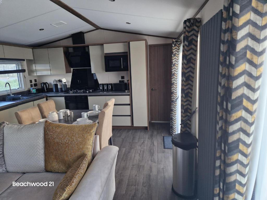 a living room with a table and chairs and a kitchen at Beachwood 21 in Camber