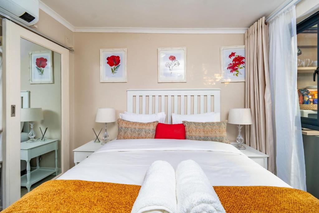 um quarto com uma grande cama branca com almofadas vermelhas em Kamuzi exquisite tiny home near airport - 2217 em Harare