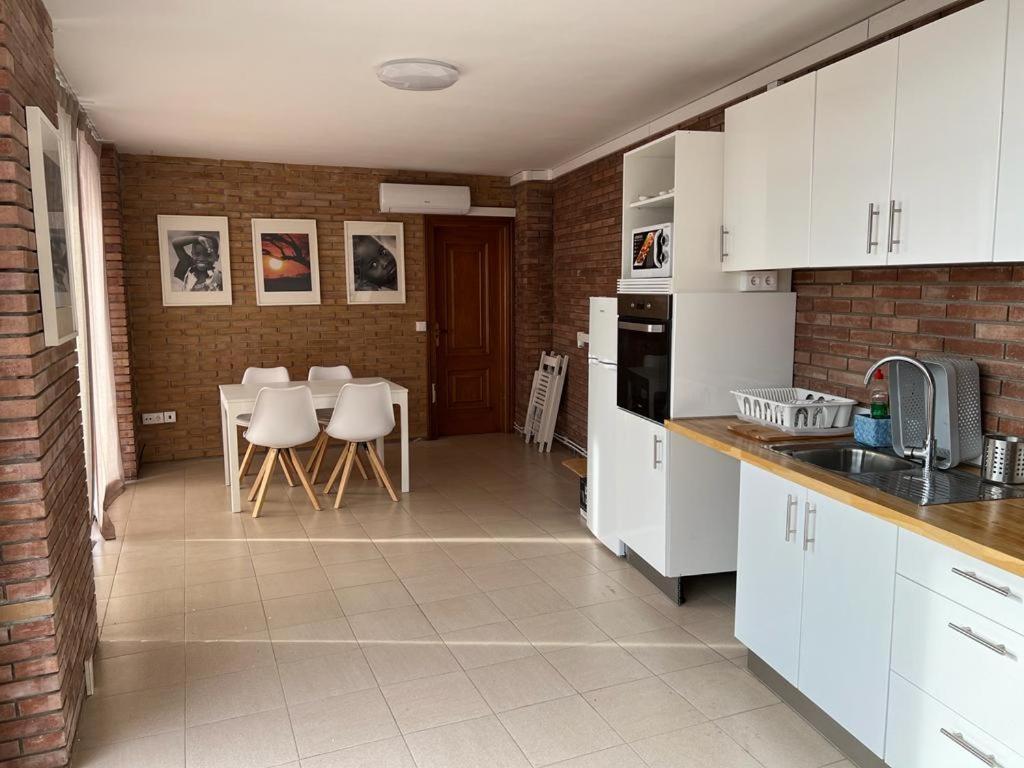 a kitchen with white cabinets and a table and chairs at APARTAM GRANOLLERS in Granollers