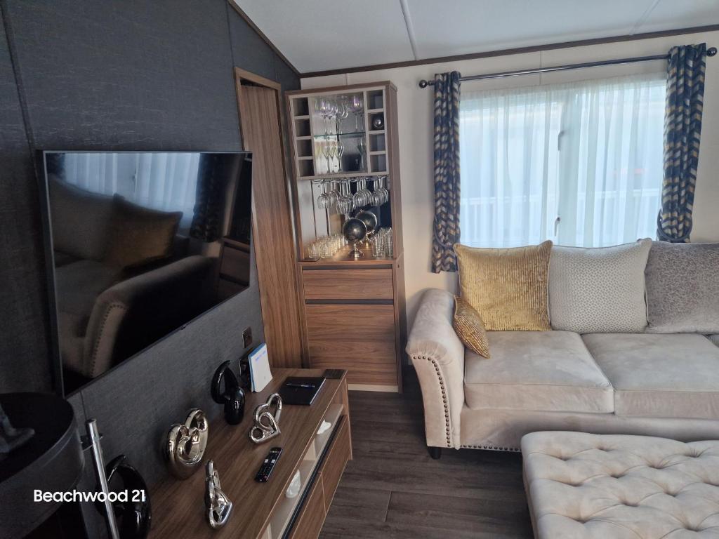 a living room with a couch and a flat screen tv at Beachwood 21 in Camber