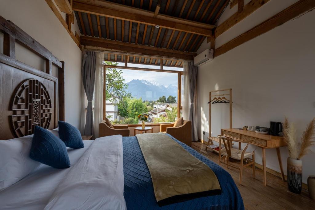 1 dormitorio con cama, escritorio y ventana en Lijiang Shitian B&B, en Lijiang