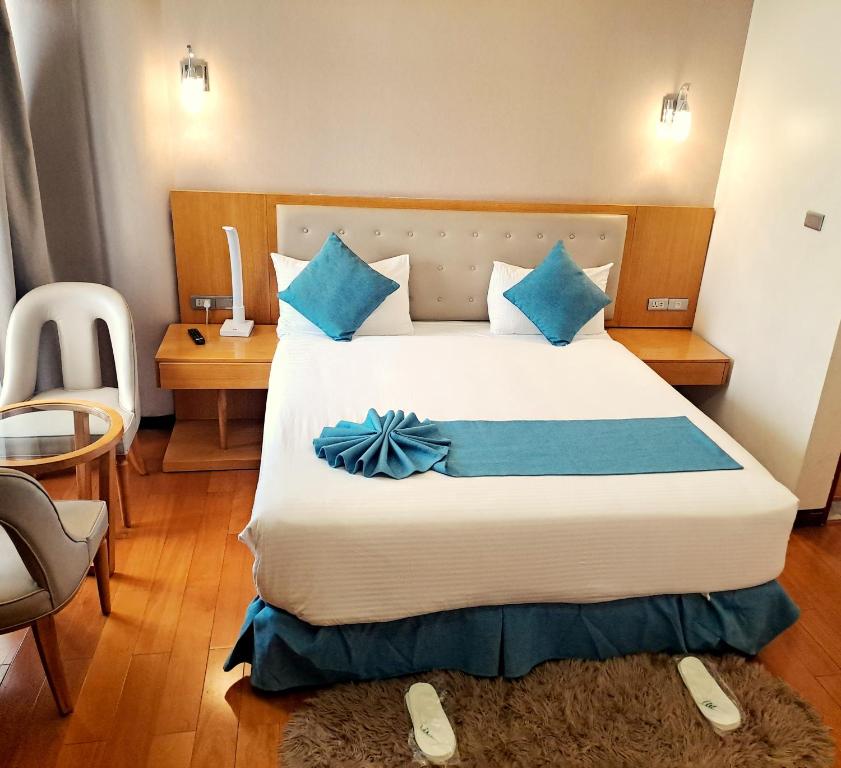 Z Addis Hotel في أديس أبابا: غرفة فندق بسرير كبير مع وسائد زرقاء