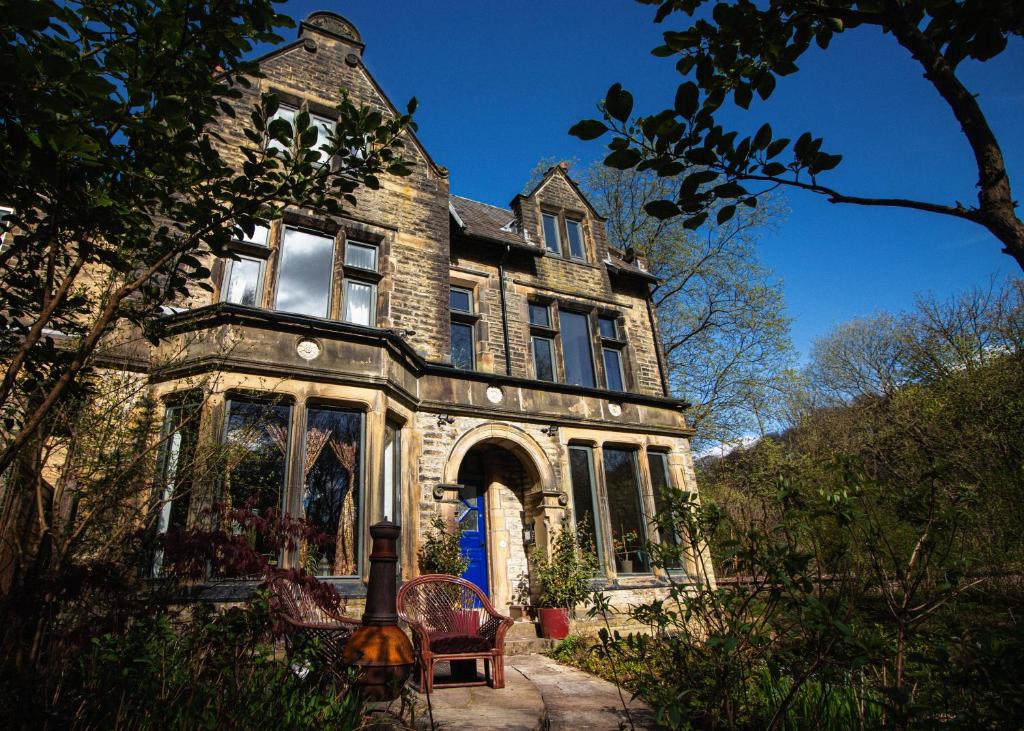 una vieja casa de piedra con una puerta azul en Crow Nest House, en Hebden Bridge