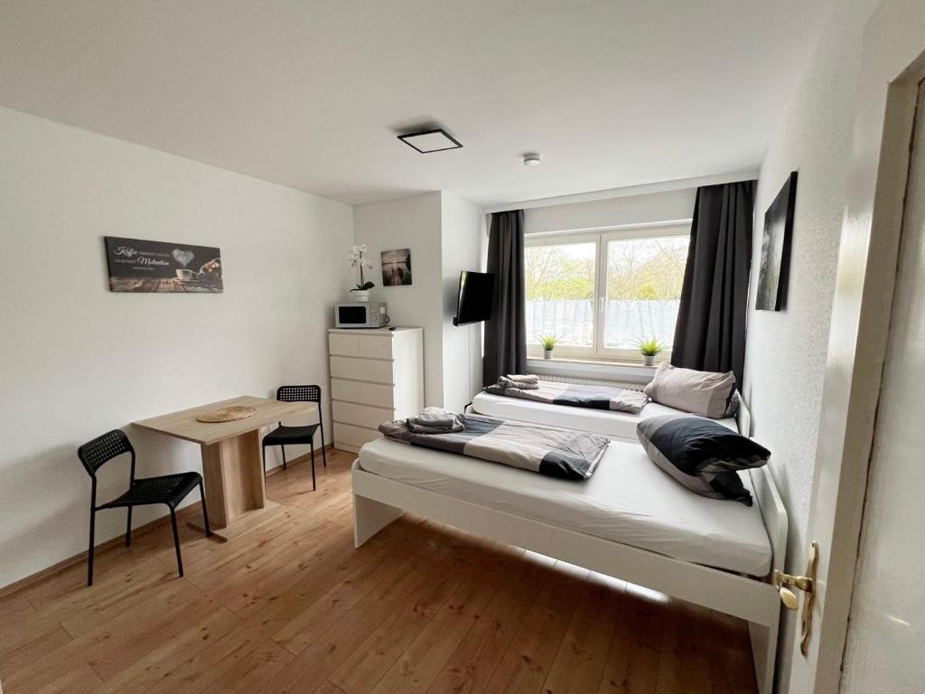 1 dormitorio con 2 camas, escritorio y ventana en Low Budget Apartment Cologne, en Colonia