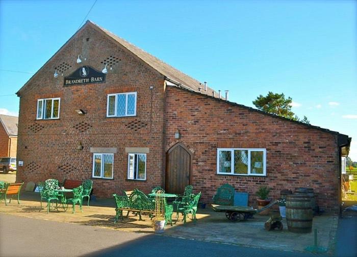 a brick building with chairs and a table in front of it at Brandreth Barn in Burscough