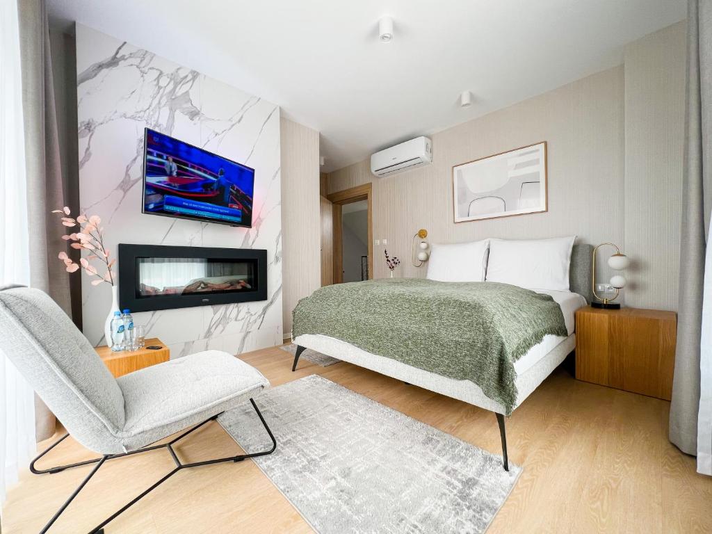 a bedroom with a bed and a chair and a tv at Cavaldi Aparthotel in Dziwnów