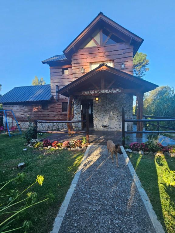 a dog standing in front of a log cabin at Cabañas Huinca Mapu - Sierra de los Padres in Sierra de los Padres