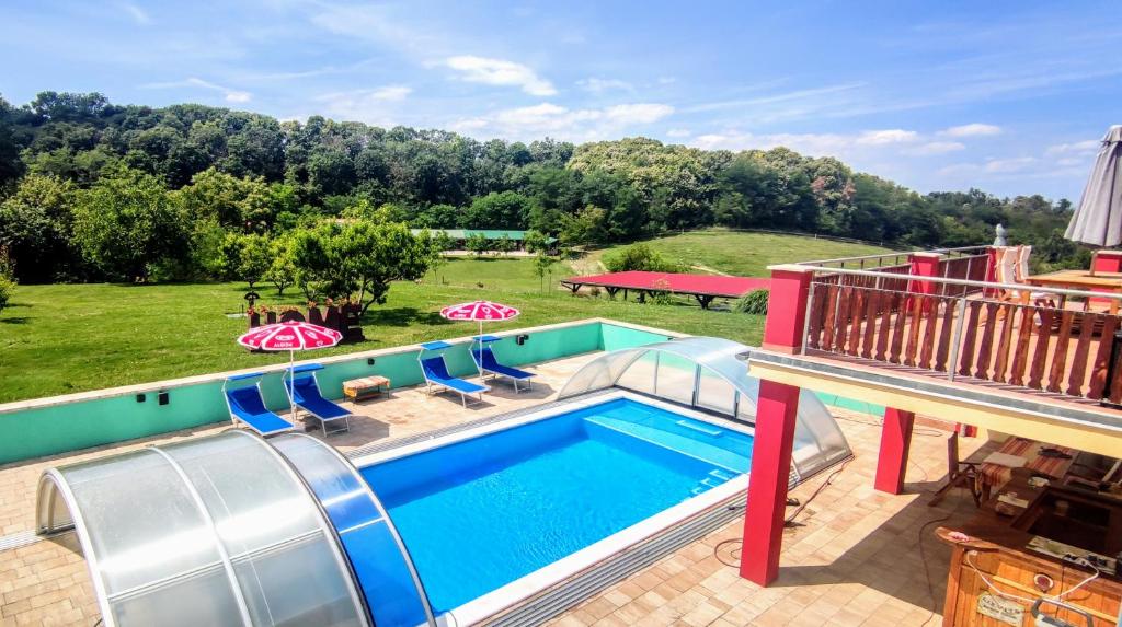 a swimming pool with chairs and a hill in the background at bellavitavilla2020 in Siófok