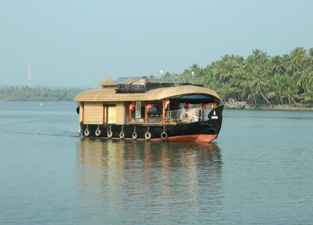 a boat with a house on the water at Sukūn Houseboats in Kannur