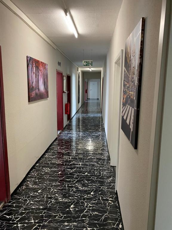 un largo pasillo con suelos de mármol negro y pinturas en las paredes en M&R Hostel en Rostock