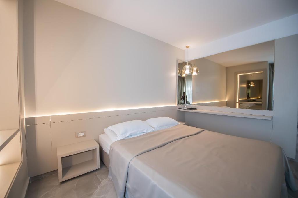 a small bedroom with a white bed and a mirror at Hotel Atena*** in Saturn