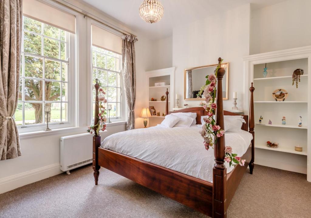 a bedroom with a bed and two windows at The Lake House - Crimplesham Hall in Stradsett