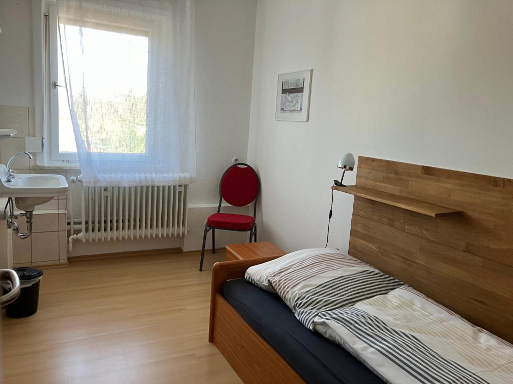 a bedroom with a bed and a sink and a red chair at Festhaus Stocksberg - Herberge 1881 in Stocksberg