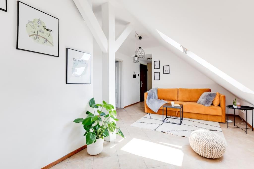 - un canapé orange dans un salon blanc dans l'établissement Cozy & Quiet Center Attic with Castle view - vtuB, à Prague