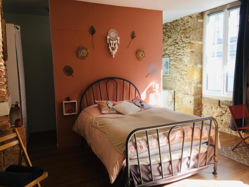 a bedroom with a bed with an orange wall at Les chambres d'Ursule in Tartas