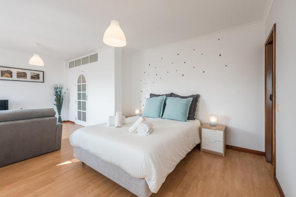 um quarto branco com uma cama grande e um sofá em GuestReady - Porto Magic View em Vila Nova de Gaia