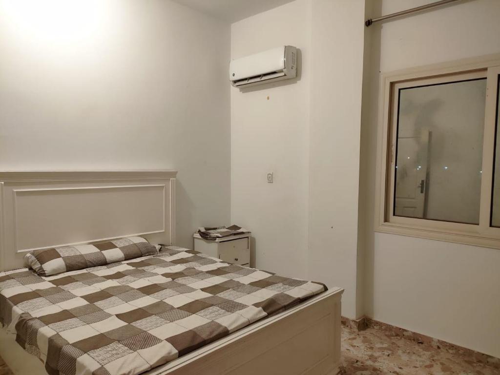 sypialnia z łóżkiem z szafką i oknem w obiekcie فيلا العائلة w mieście ‘Ezbet Sharikât Wardan