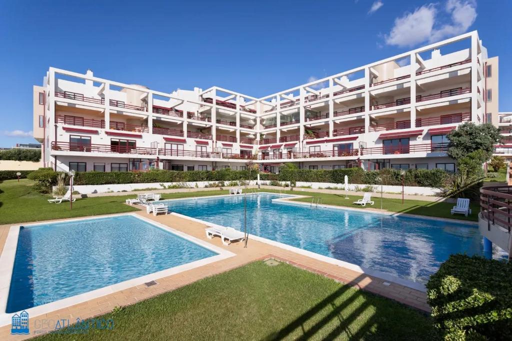 un gran edificio con una piscina frente a él en Gaia Beach & Pool Residence - Porto South Seashore, en Vila Nova de Gaia