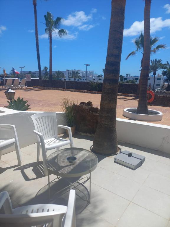 eine Terrasse mit Stühlen, einem Tisch und Palmen in der Unterkunft Club Del Mar No.8 in Puerto del Carmen