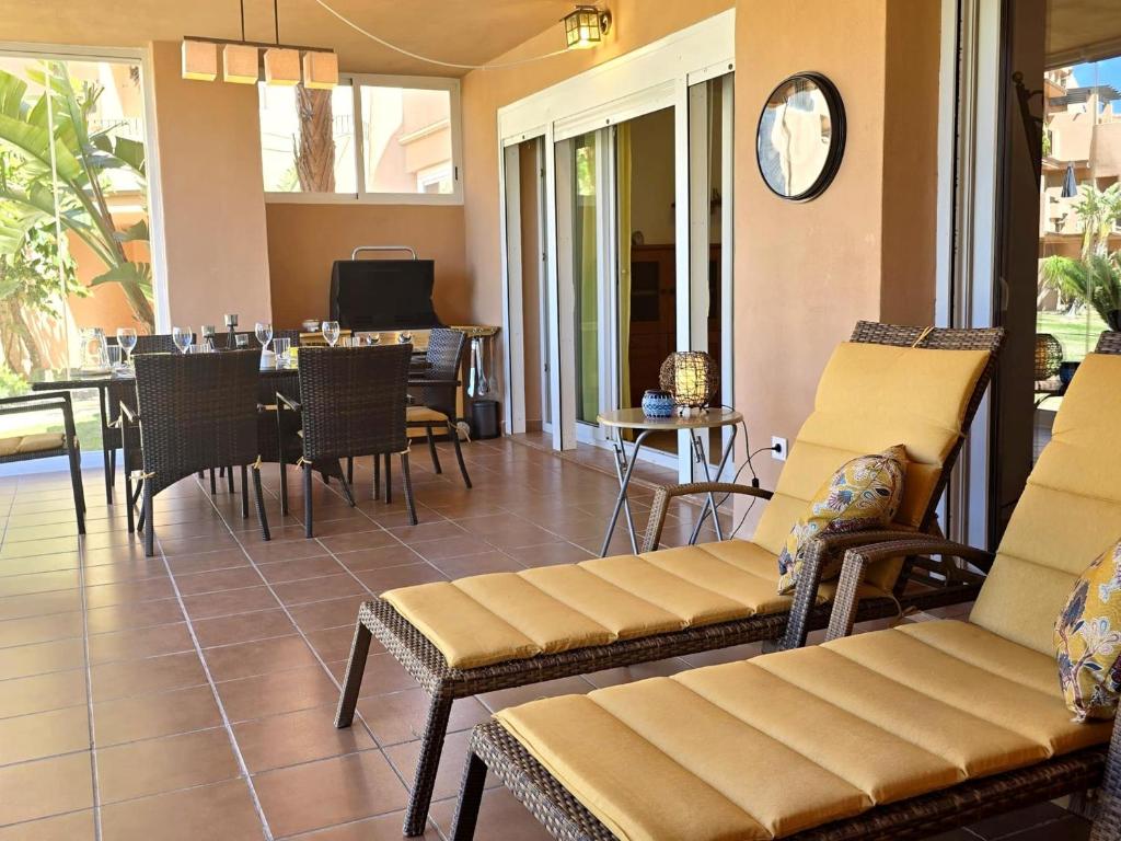 a patio with chairs and tables and a clock on the wall at Espliego Pool View Apartment in Torre-Pacheco