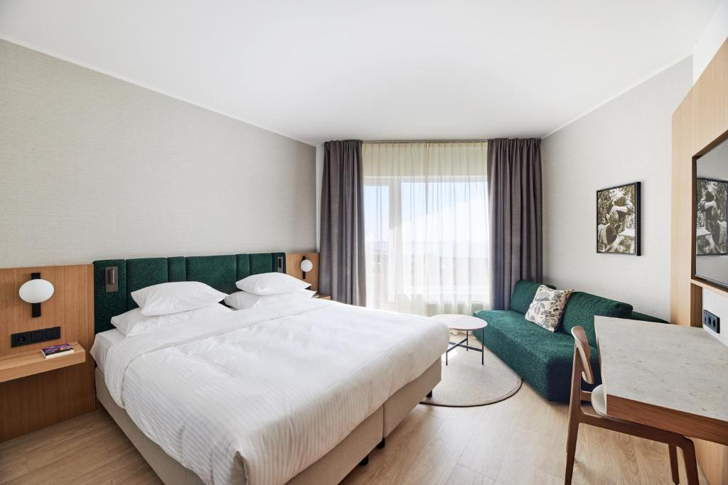 um quarto de hotel com uma cama grande e um sofá em Georg Ots Spa Hotel em Kuressaare