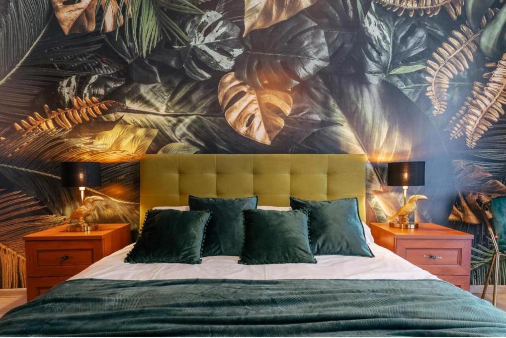 a bedroom with a large bed with a painting on the wall at JUNGLE in Kołobrzeg