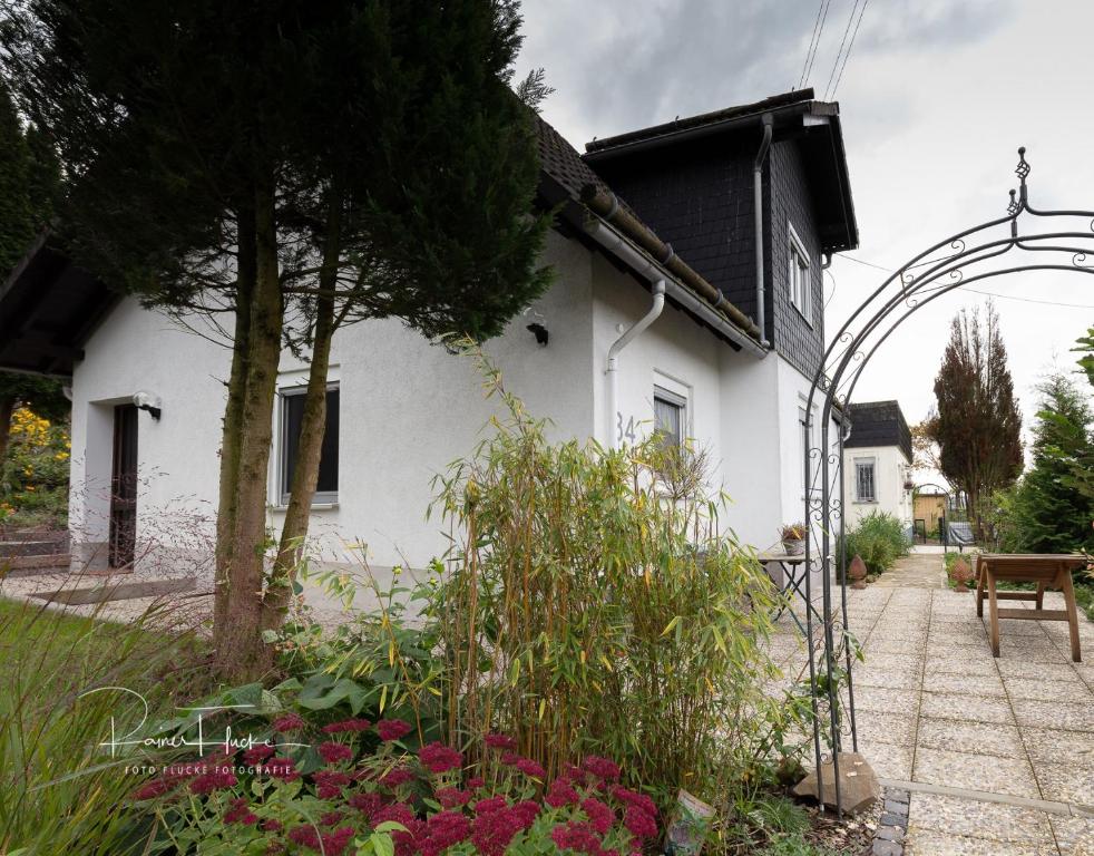 uma casa branca com um arco num jardim em Ferienhaus Specht em Schotten