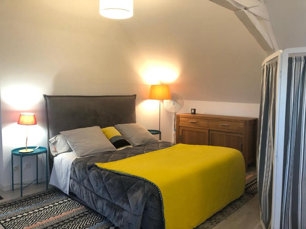 1 dormitorio con 1 cama amarilla y 2 lámparas en Ecrin de Verdure en Sainte-Suzanne