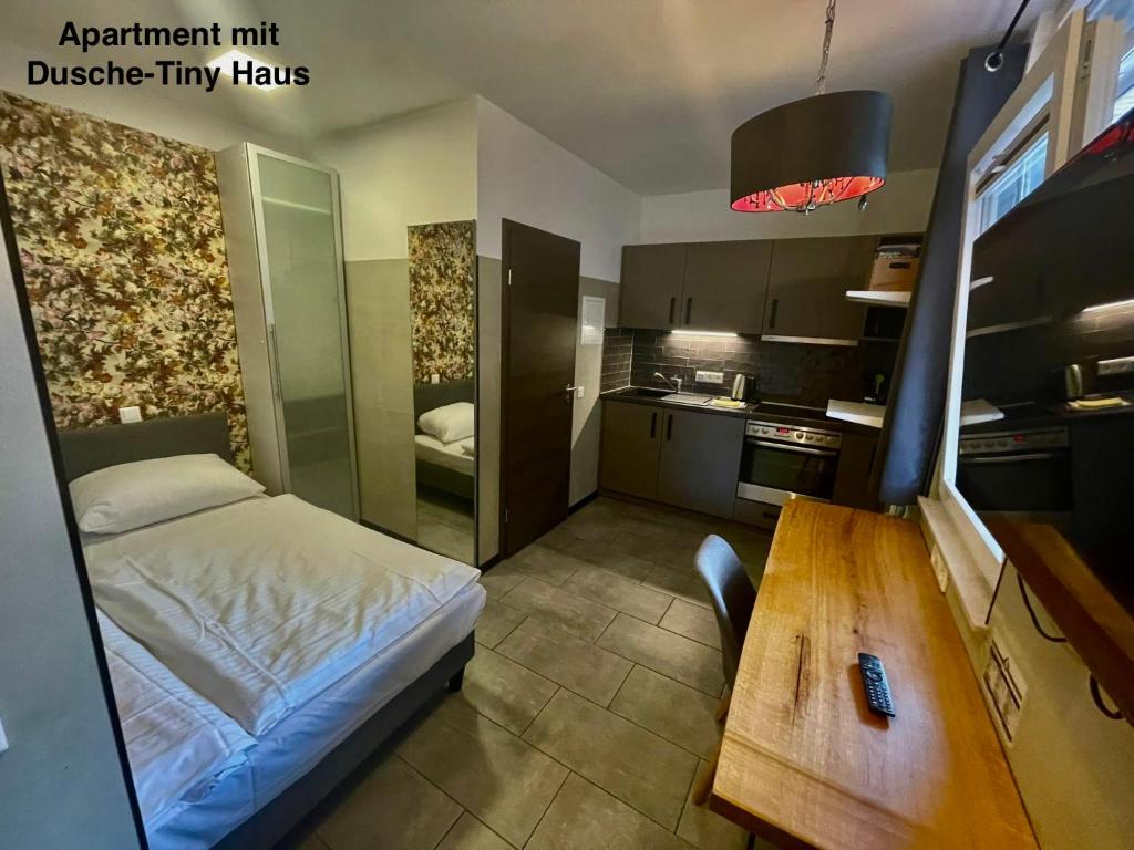 een kleine slaapkamer met een bed en een houten tafel bij KobyApartment TinyHaus in Herford