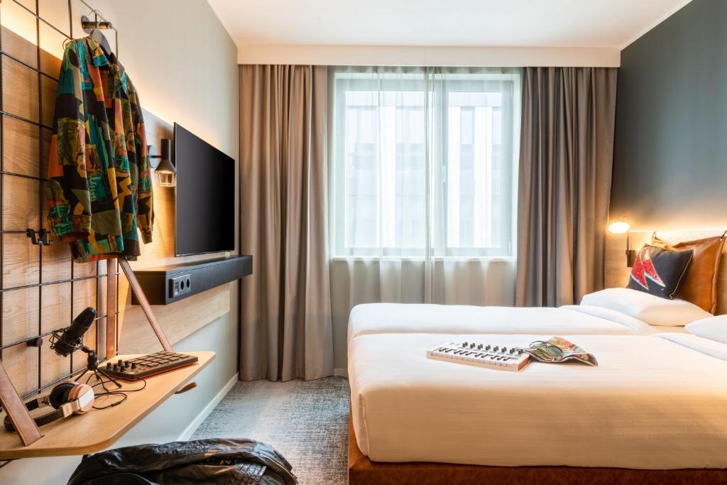 a hotel room with two beds and a desk at Moxy Berlin Airport in Schönefeld