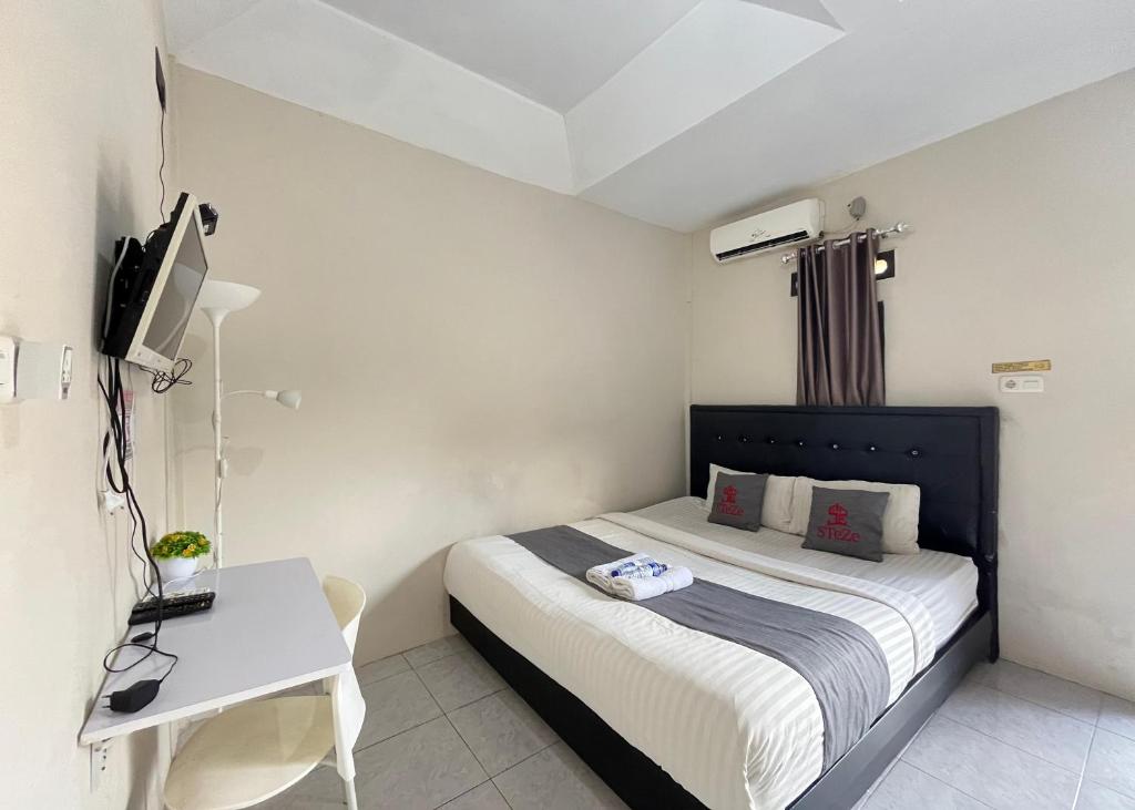 a bedroom with a bed and a desk and a television at Steze Guesthouse Syariah Telanaipura in Jambi