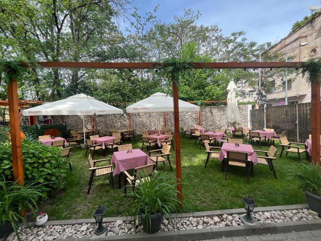 un patio esterno con tavoli, sedie e ombrelloni di House of Tourists Garden and More a Bucarest