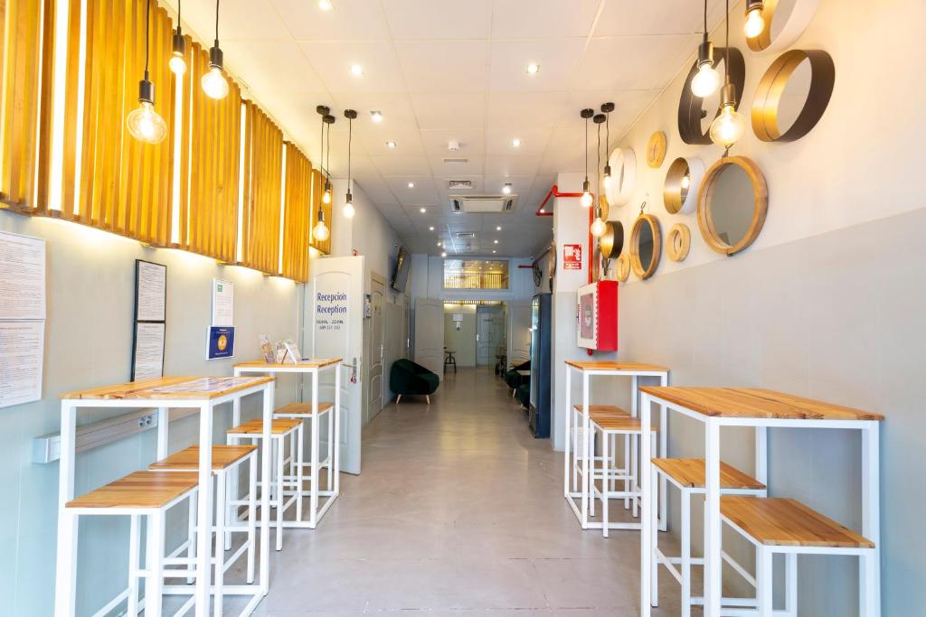 una fila de mesas y taburetes en un restaurante en Malaga Stop Hostel AB, en Málaga