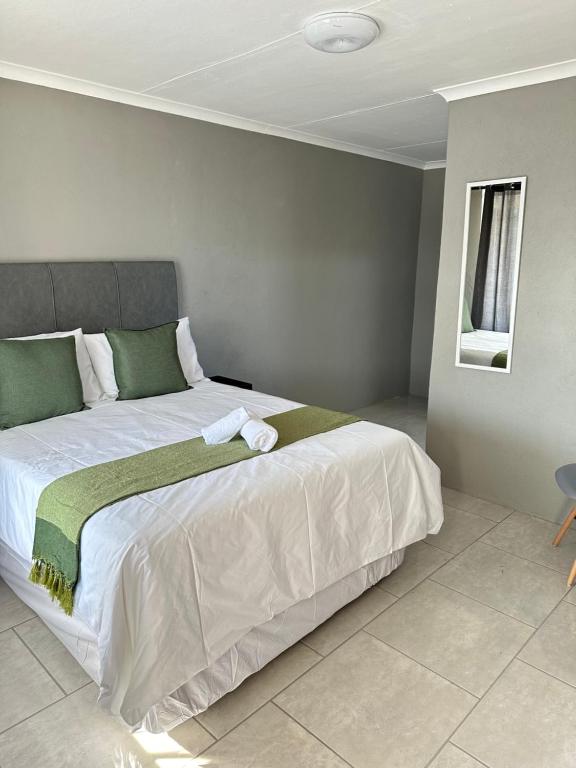a bedroom with a large bed with white sheets and green pillows at Maphuthi River Lodge in Ga-Manapane