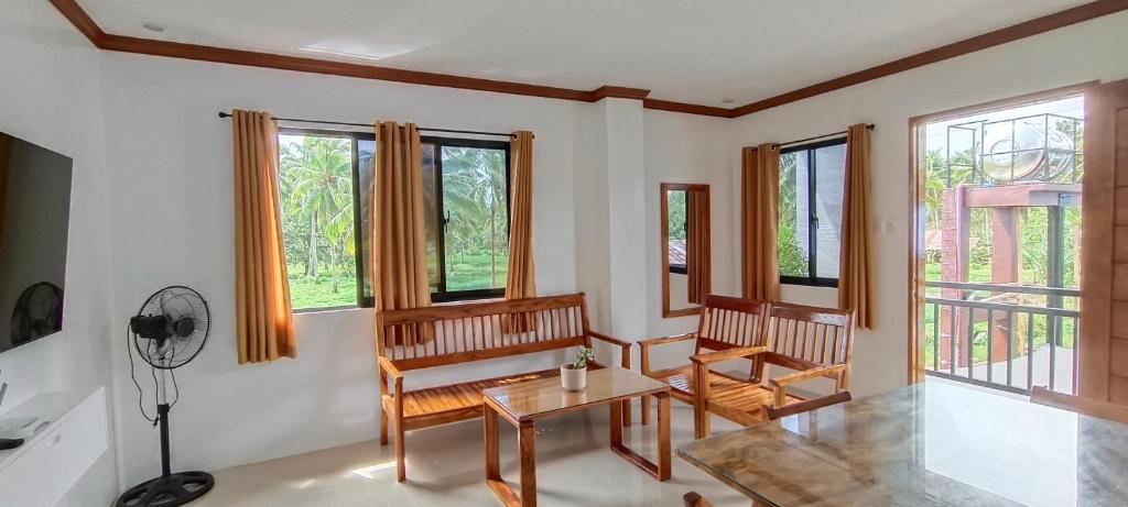 a living room with chairs and a table and windows at Casa Victoria Pension House-Star Maria in Somosomo