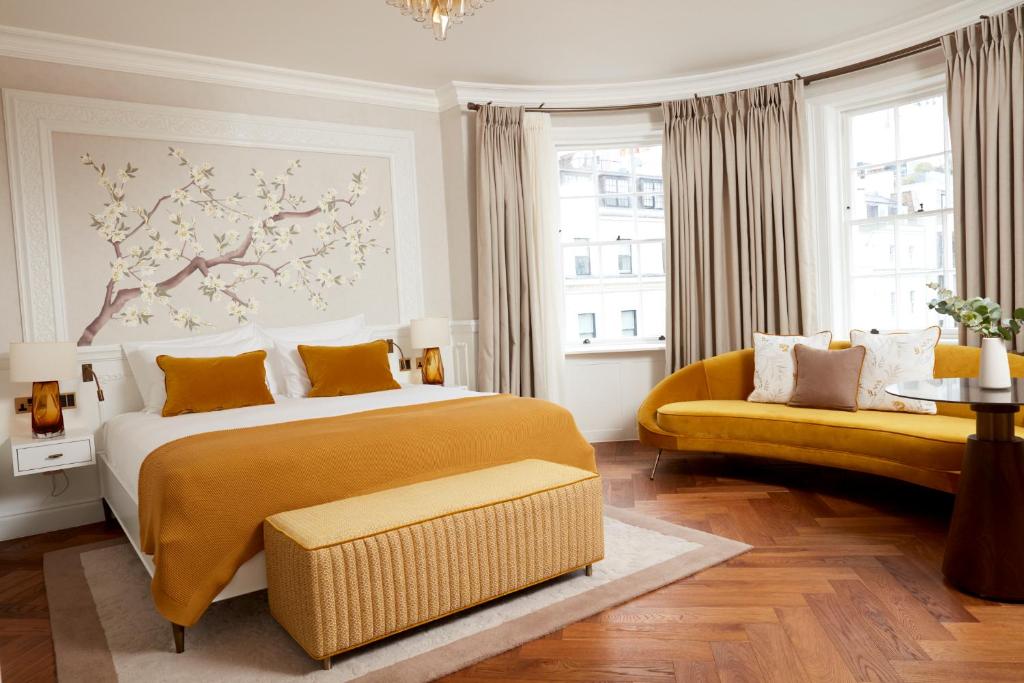 a bedroom with a large bed and a yellow couch at 2 Chesham Hotel in London