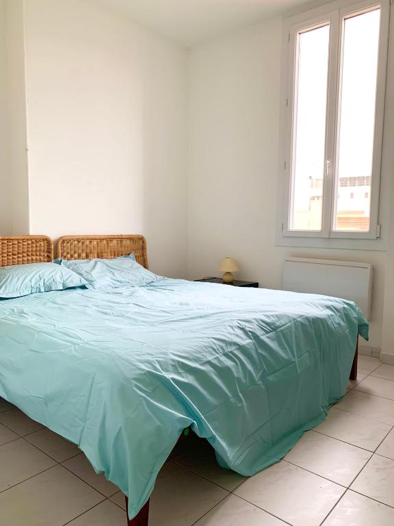 a bed with a blue comforter in a bedroom at Festival de Cannes apartment in Cannes