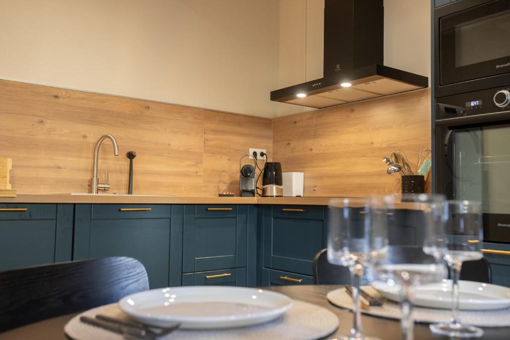 una cucina con armadi blu e un tavolo con bicchieri di L'antiquaire - 3 chambres - Hypercentre - Wifi a LʼIsle-sur-la-Sorgue