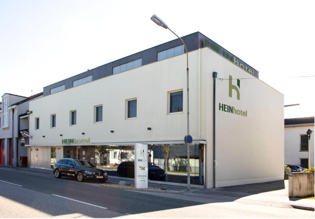 un edificio bianco con un'auto parcheggiata di fronte di HEINhotel vienna airport a Schwechat