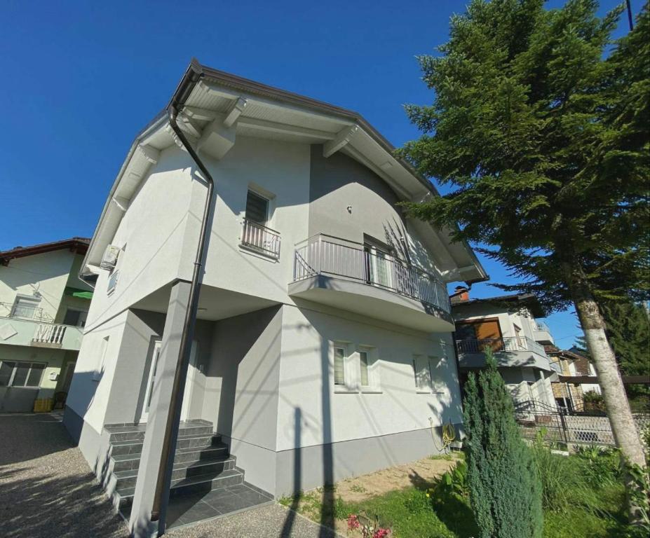 a white building with a pole next to a tree at Apartman Nani in Bihać