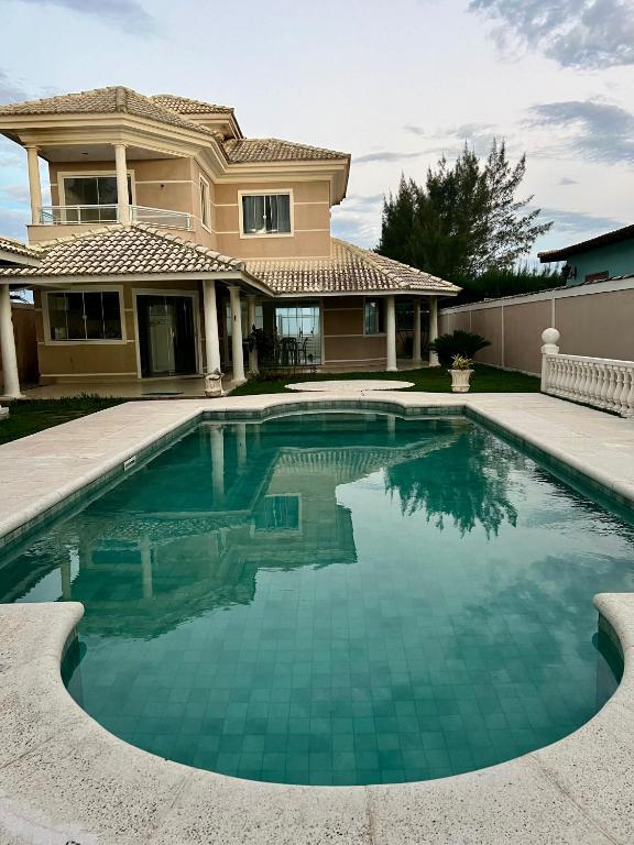 a house with a swimming pool in front of a house at Casa refúgio de paz in Cabo Frio