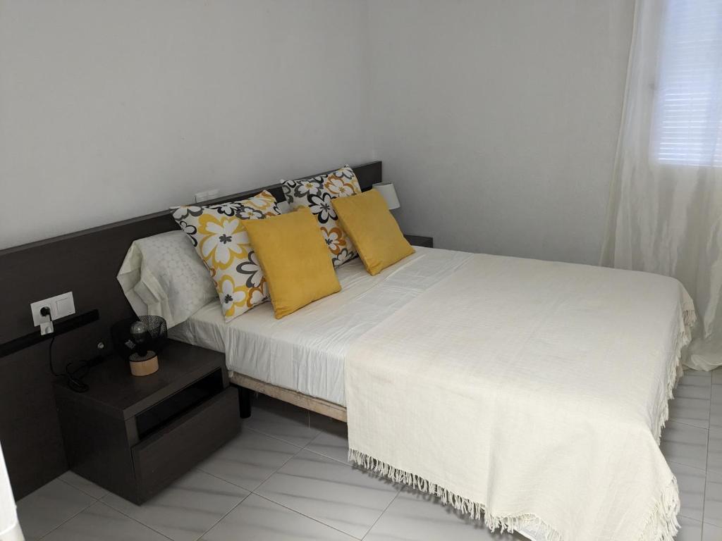 - une chambre avec un lit doté de draps blancs et d'oreillers jaunes dans l'établissement ALCANAR DEL MAR, à Les Cases d'Alcanar