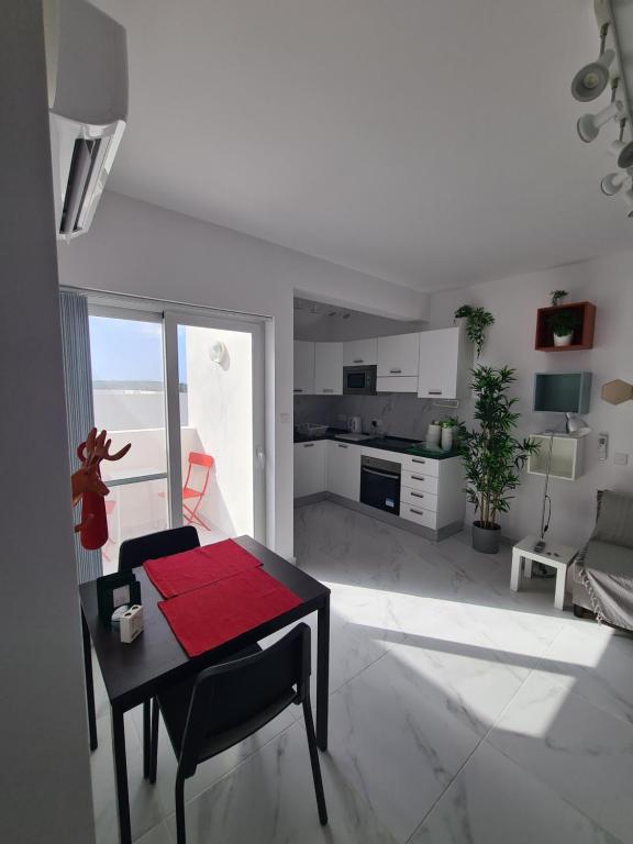 een witte woonkamer met een tafel en een keuken bij Top Floor with terrace and 5 mins walk to centre in Marsaskala